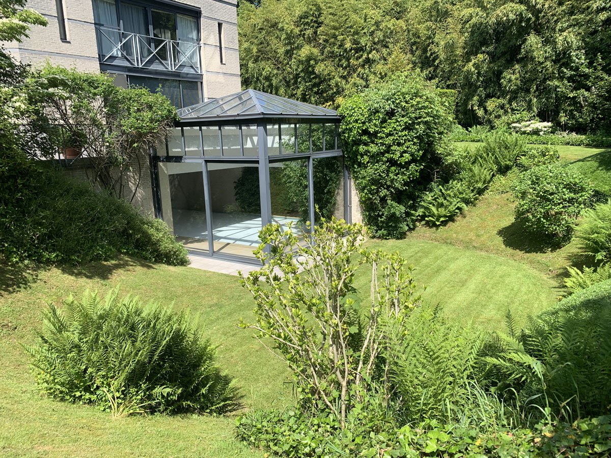 Jardin avec plantations et serre vitrée